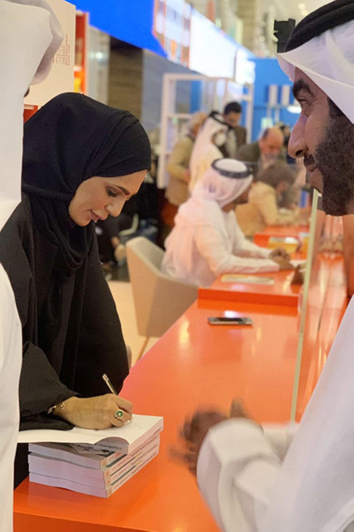 توقع على أحد مؤلفاتها في معرض الشارقة الدولي للكتاب